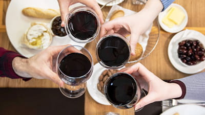Brasserie wine bar - quatre personnes tenant haut un verre de vin rouge