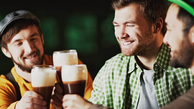 Irish bar - trois amis buvant une pinte de bière au bar