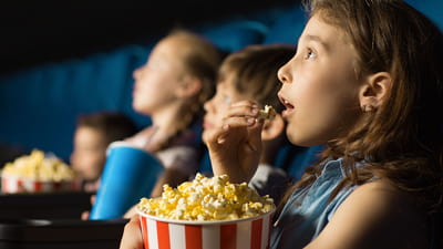 Kinderfilms - rij kinderen met popcorn die naar een film kijken
