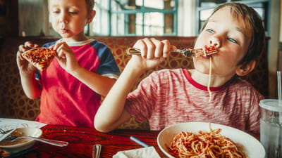 Kids' meals Kids' dinner time - two children eating spaghetti