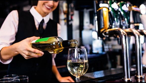 Bar - woman pouring glass of white wine at a bar