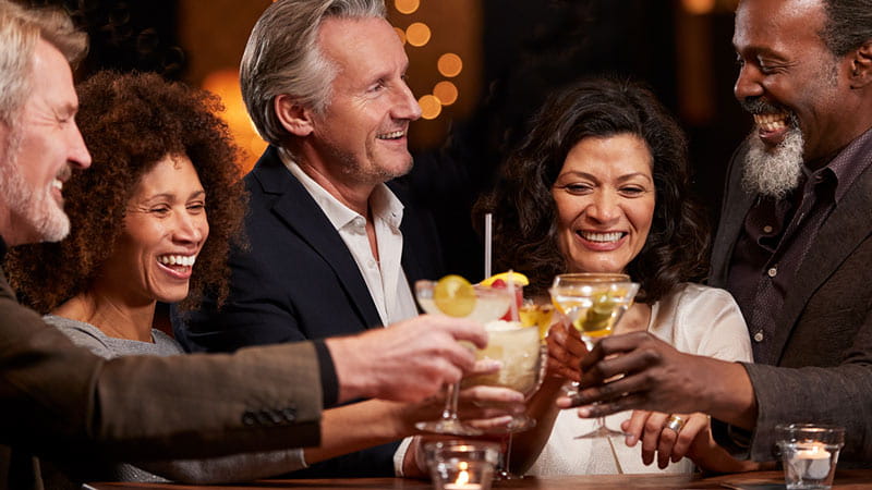 Sunset Show Bar – Männer und Frauen im mittleren Alter genießen Cocktails in einer Bar